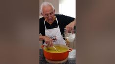 an old man is mixing something in a pot