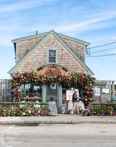 a building with flowers on the outside and people walking by it in front of it