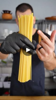 a man in black gloves holding up some pasta