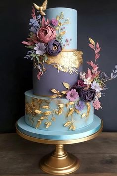 a blue and gold cake with flowers on top