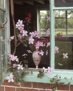 a vase with flowers in it sitting on a window sill next to a brick wall