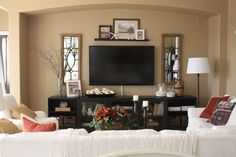 a living room filled with furniture and a flat screen tv mounted on the wall over a fireplace