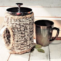 a coffee mug sitting on top of a wooden table next to a rope wrapped container