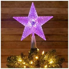 a purple lighted star on top of a christmas tree