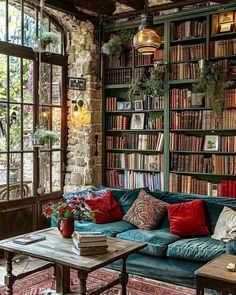 a living room filled with lots of books and furniture next to a window covered in plants