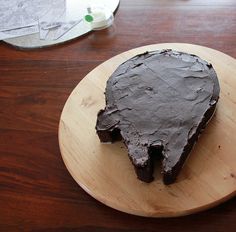 a piece of chocolate cake sitting on top of a wooden plate next to a knife