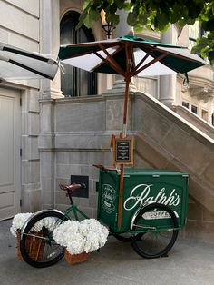 a green bike parked next to a building with an umbrella over it's head