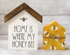 a small house next to a beehive with the words home is where my honey bee