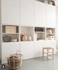 an empty room with white cabinets and baskets on the shelves, next to a wooden chair