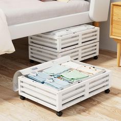 a white bed sitting next to a wooden table on top of a hard wood floor