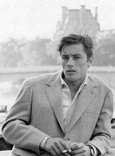 black and white photograph of a man in a suit sitting on a bench looking at the camera