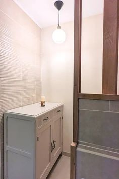 a cabinet in the corner of a room with a light on above it and a lamp hanging from the ceiling