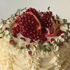 a cake with white frosting and pomegranates on top