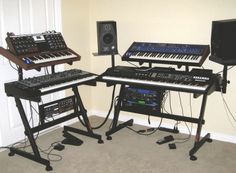 there are three keyboards and two monitors in this room with the music equipment on display