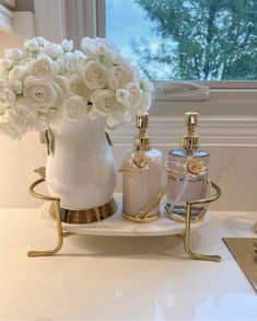 a white vase filled with flowers sitting on top of a counter next to two bottles