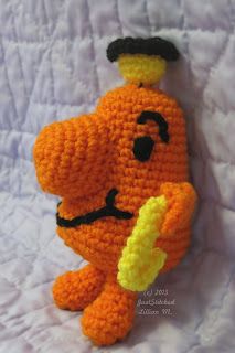 an orange crocheted stuffed animal holding a banana