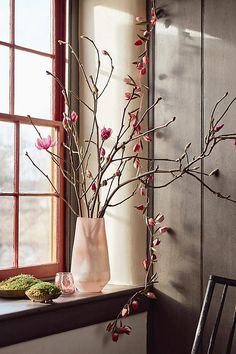 a vase filled with pink flowers sitting on top of a table next to a window