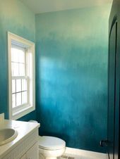 a white toilet sitting in a bathroom next to a sink under a window with blue paint on the walls