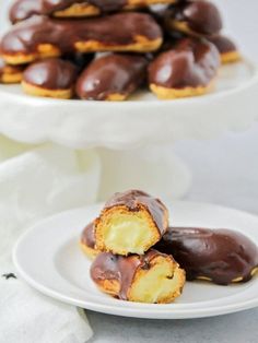 chocolate covered doughnuts are on two white plates