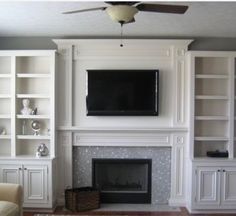 a living room with white bookcases and a fireplace