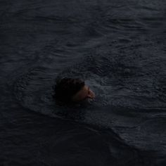 a man swimming in the water at night with his head above the water's surface