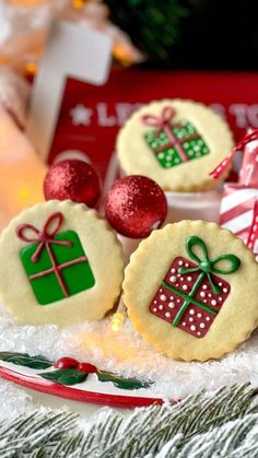 three decorated cookies sitting on top of a white plate next to candy canes and christmas decorations