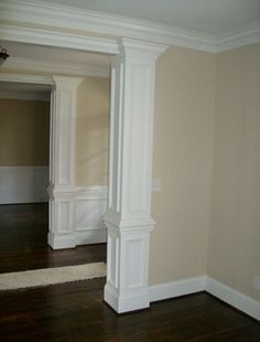 an empty room with wood floors and white columns in the corner, along with hard wood flooring