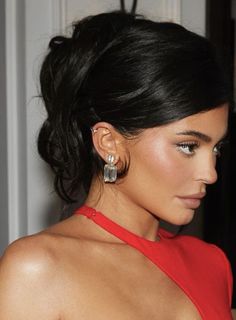 a woman in a red dress wearing large earrings