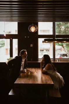 a man and woman sitting at a wooden table