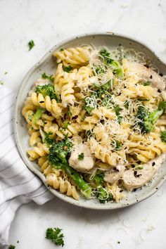 a bowl filled with pasta and broccoli on top of a white tablecloth