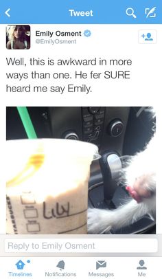 a cat sitting in the driver's seat of a car next to a cup