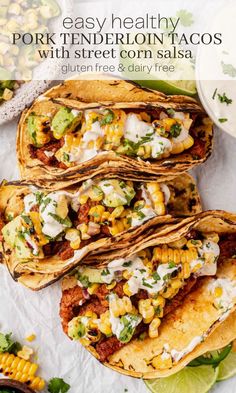 four mexican tacos with corn and avocado on top, sitting on a plate