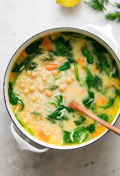 a pot filled with soup and vegetables on top of a white counter next to a lemon