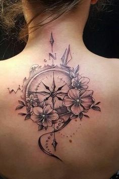 a woman's back with a clock and flowers tattoo on her upper back neck