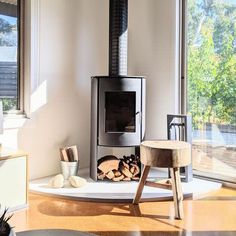 a wood burning stove in a living room next to a large window with lots of windows