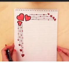 someone holding a notepad with hearts on it and writing down the page in front of them