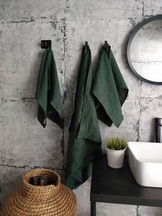 a bathroom with green towels hanging on the wall next to a basket and sink in front of a mirror