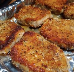 four pieces of meat sitting on top of tin foil covered in sauce and seasoning