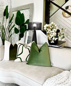 a living room filled with white furniture and lots of greenery on top of it