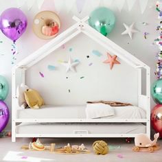 a room with balloons and confetti on the walls, including a bed frame