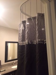 a bathroom with a shower curtain that has beads hanging from it's side, and a mirror in the background