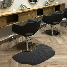 two black chairs sitting in front of a mirror on top of a wooden table with mirrors above it