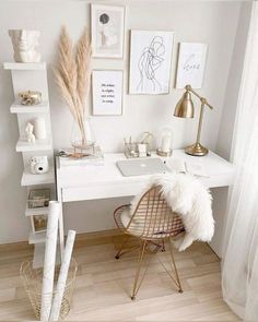 a white desk with some pictures on the wall and a chair in front of it