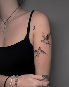 a woman wearing a black tank top with birds on her arm