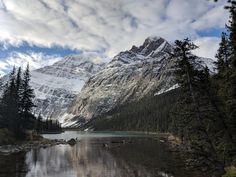 the mountains are covered with snow and trees near a lake in the middle of nowhere