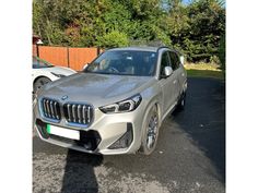 a silver bmw suv parked next to another car