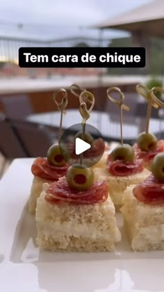 small appetizers with olives and cheese on them sitting on a white plate