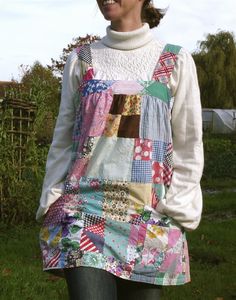 a woman standing in the grass wearing a patchwork dress