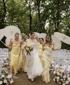 the bridesmaids are walking down the aisle with their umbrellas