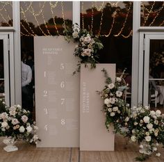 a table with flowers and greenery on it next to a large sign that says the wedding date